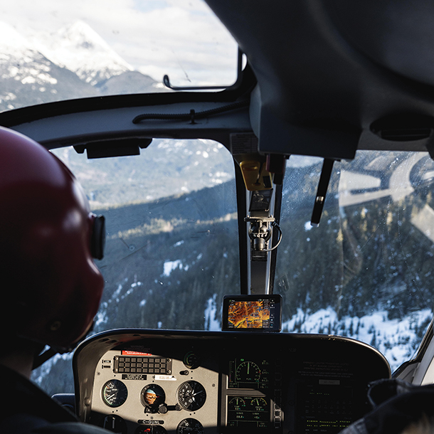 Cockpit view in helicopter overlooking snow covered mountains  